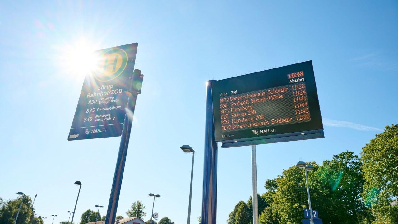 Digitale Abfahrtstafel an einem Busbahnhof im Gegenlicht der Sonne